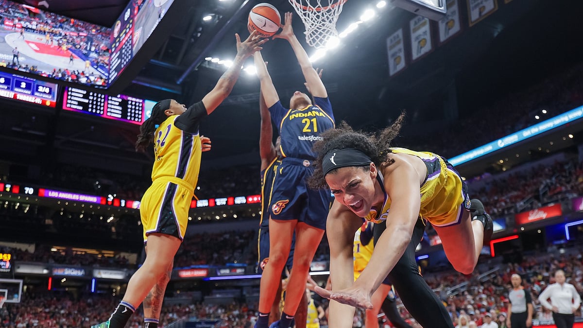 Rae Burrell #12 of the Los Angeles Sparks falls to the ground as Emma Cannon #32 of the Los Angeles Sparks and Makayla Timpson #21 of the Indiana Fever reach for the ball during the second half at Gainbridge Fieldhouse on July 5, 2025 in Indianapolis, Indiana.