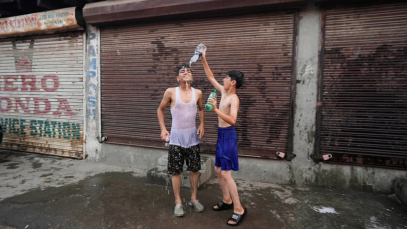 A boy pours water on his friend as they cool off on a hot summer day in Srinagar, Kashmir.