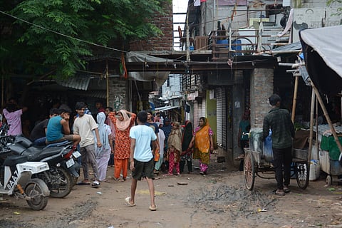 Women and children stand outside their homes due to no electricity as summer heat peaks