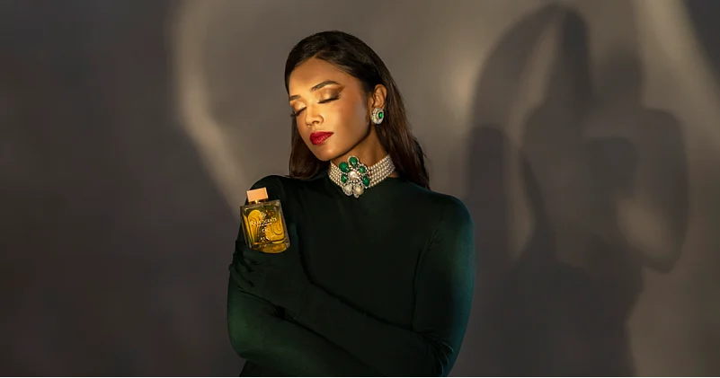 Model holding a perfume bottle with closed eyes