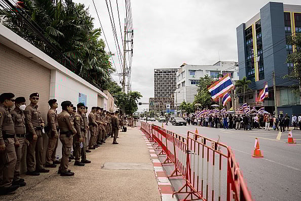(Photo by Ploy Phutpheng/SOPA Images/LightRocket via Getty Images) : Thai police officers line up in front of the Cambodian Embassy in Bangkok as protesters gather across the street. 