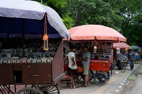 Along the roadside, vendors, mostly from the settlement, sell mobile phone accessories alongside small general stores.
