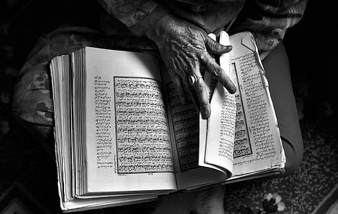 "I keep my son's photo in the Quran so that I can see it every morning when I open  it", says Dilshada, who is in her late 50s. "I still wish he just appears at the window one day and says, ‘Mouji be owusaye’ (Mama, I’ve come)", she adds. | Yasir Iqbal
