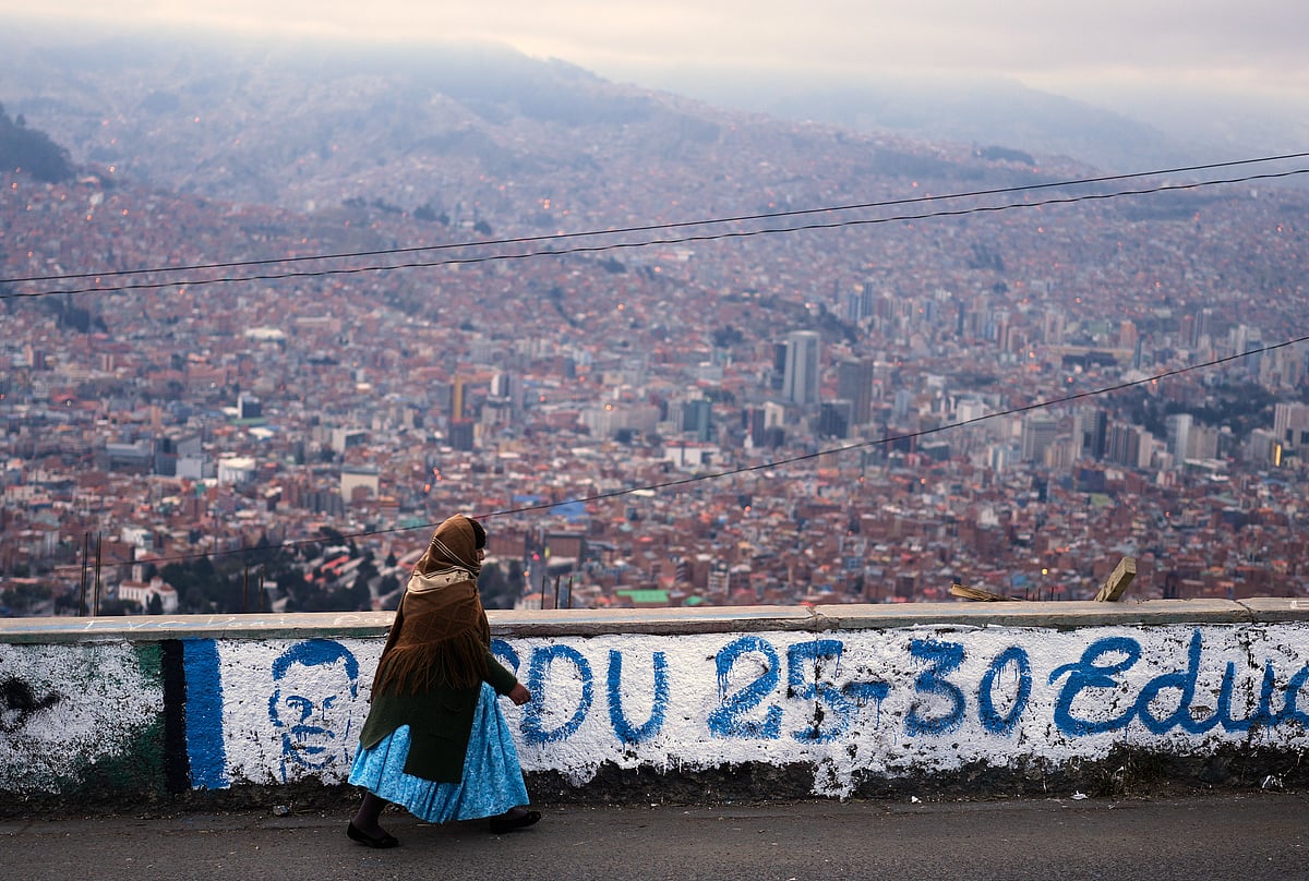 (AP Photo/Juan Karita) : A woman walks past campaign murals for presidential candidates prior to Sunday's presidential and legislative elections in El Alto, Bolivia, Thursday morning, Aug. 14, 2025. 