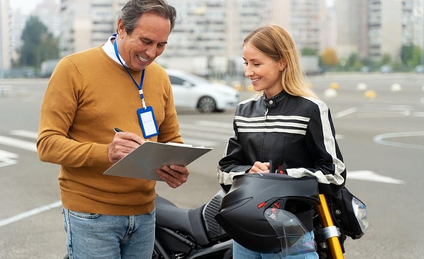 A man & woman standing next to a motorcycle, discussing insurance details