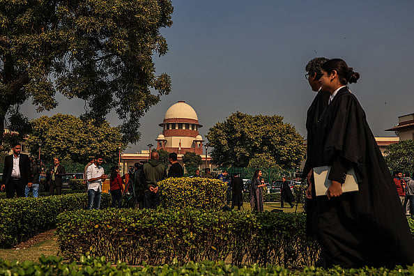 A woman lawyer walks by the Supreme Court building in her robes - Getty