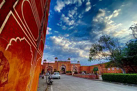 A breathtaking glimpse of Jaipur's iconic Ajmeri Gate under a dramatic morning sky.