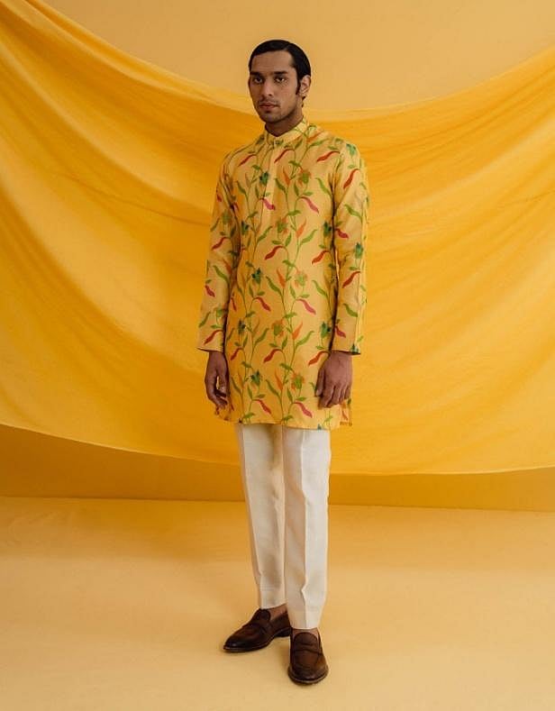 A man wearing a yellow floral kurta set, posing on a light background.