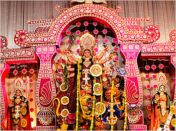 An ornate archway frames a statue of the goddess Durga and other deities.