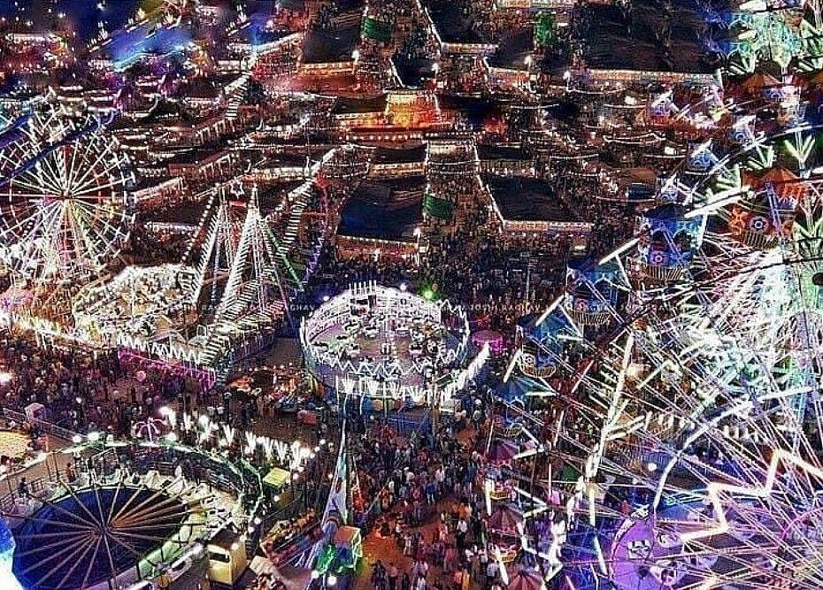 A aerial view of a brightly lit and bustling fairground at night