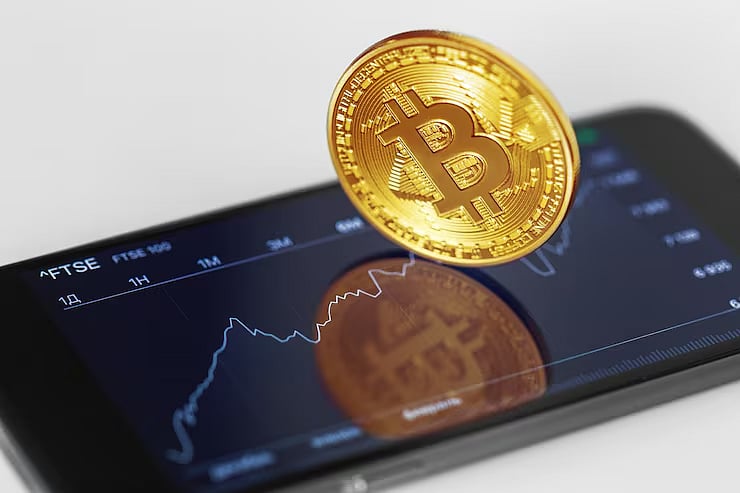 Bitcoin coin placed on a smartphone screen showing a price chart.