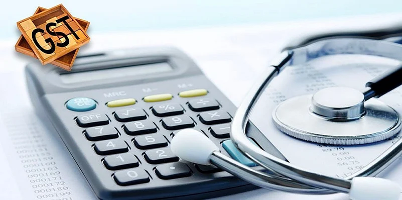 A calculator next to a stethoscope with GST text written on top left corner