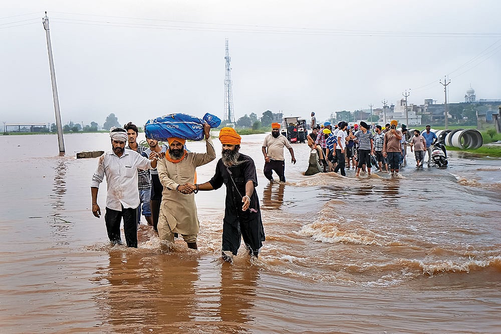 Photo: PTI : Water, Water Everywhere: Locals assist in moving flood affected people to a safer place as floodwater enters villages in Ajnala, near Amritsar 