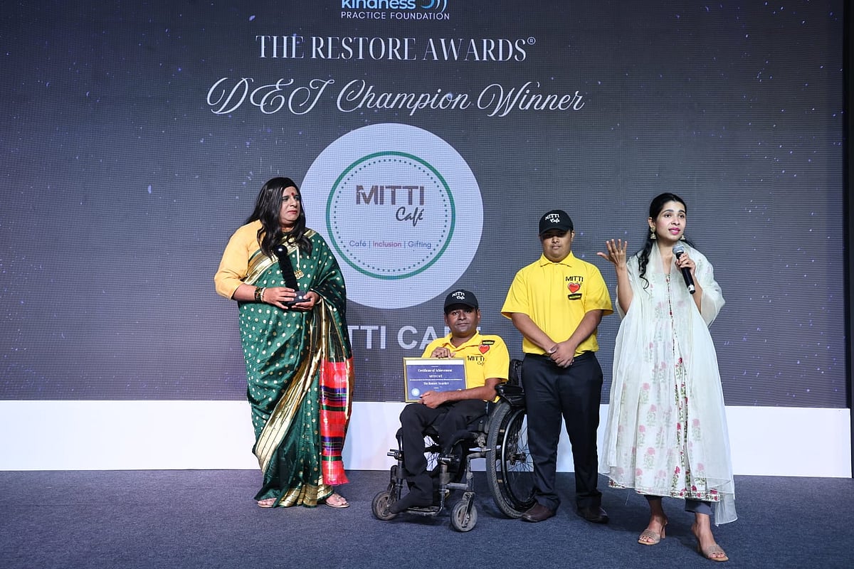 A photo of three people, including one in a wheelchair on a stage.