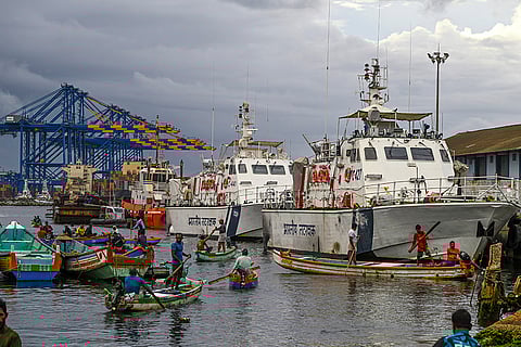 Fishermen row past Indian Coast Guard ships
