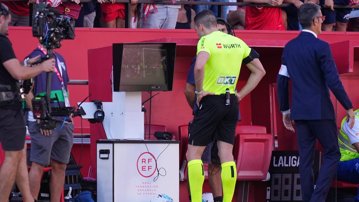 Referee Alejandro Muniz Ruiz pauses the match and checks the VAR screen during the Spanish La Liga soccer match between Sevilla and Barcelona at the Ramon Sanchez Pizjuan stadium in Seville, Spain, Sunday, Oct. 5, 2025.