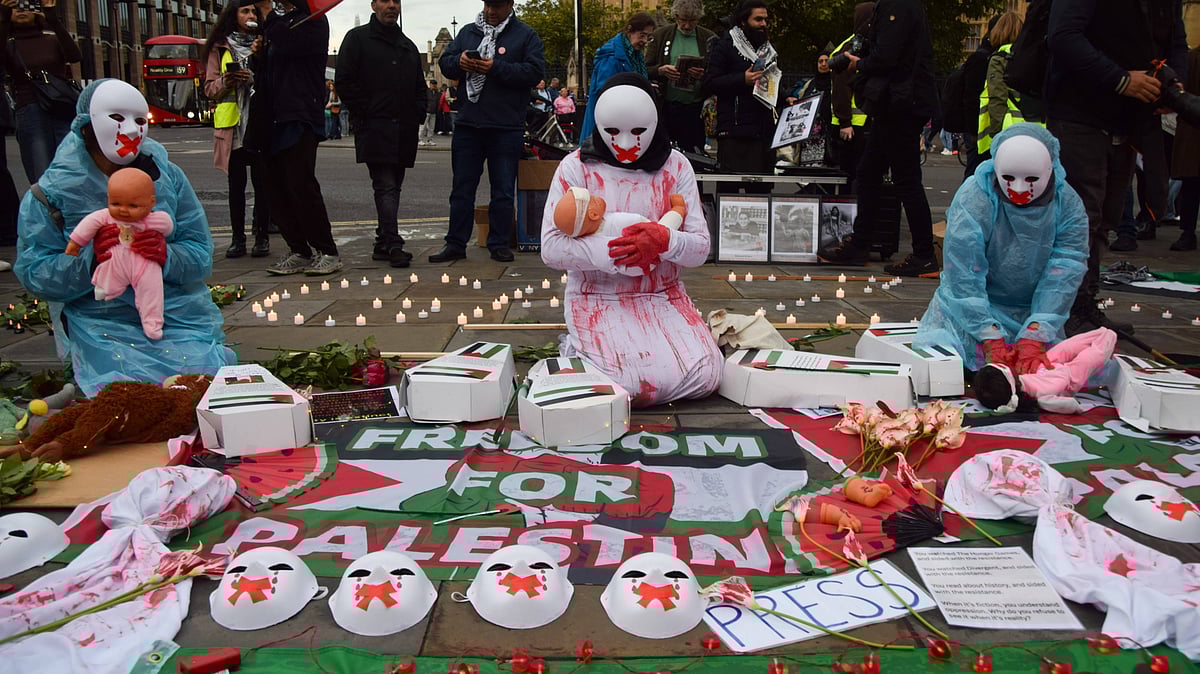 imago | : Protesters wearing masks hold dolls representing hurt and dying children as Palestine supporters stage a vigil in Parliament Square for over 41,000 people killed in Gaza on the first anniversary of the Israel-Hamas war, which began when Hamas killed and abducted Israelis at the Nova music festival on 7th October 2023.