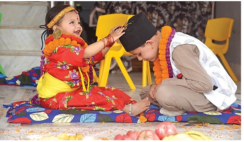 Young girl applying a tika to her brothers forehead during Bhai Tika or Bhai Dooj.