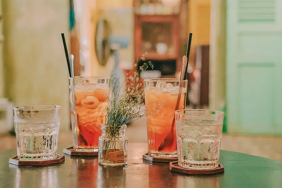 Two cocktails and two glasses of water, with straws, on a table.