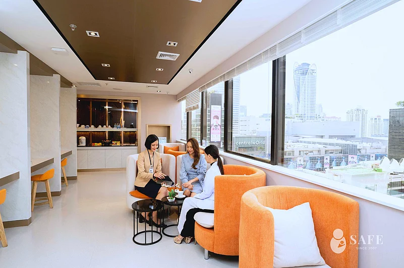 People in a modern room with orange couches and a city view