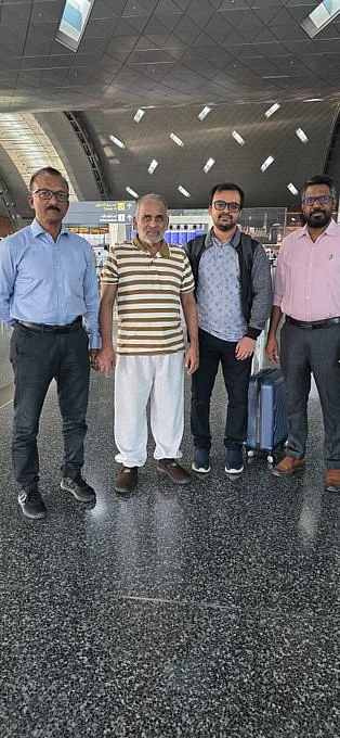 4 men posing for a photograph at an airport