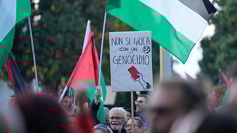 People hold a banner reading "you don't play with genocide" as they protest against the participation of the Israeli national team in the 2026 Soccer World Cup qualification match against Italy being played in the evening in Udine, Italy, Tuesday, Oct. 14, 2025