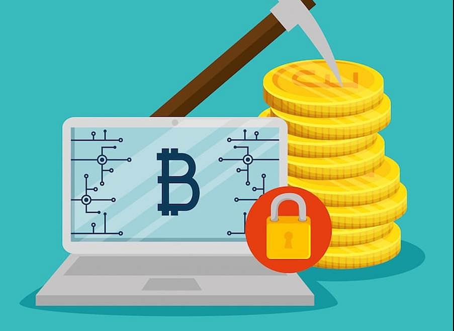 A laptop with a Bitcoin symbol on the screen, next to a stack of gold coins