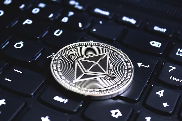 A close-up of a coin with the Ethereum logo on a dark keyboard.