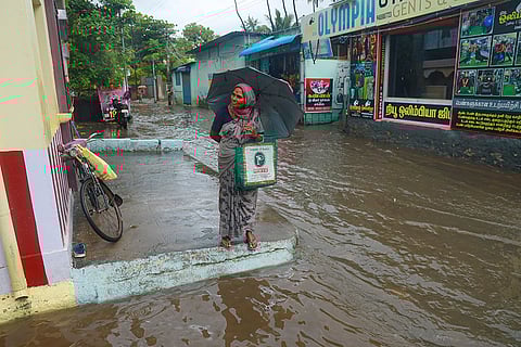 A commuter waits on an elevated section of a waterlogged road amid rain, at Nagercoil in Kanniyakumari district, Tamil Nadu.