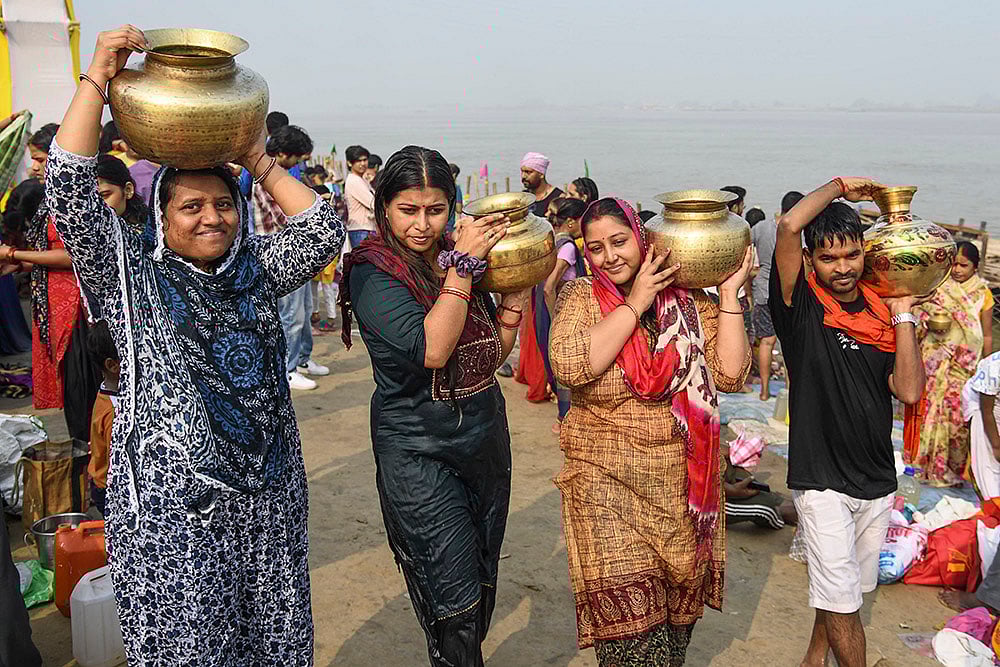 | Photo: PTI : People carry water-filled vessels after offering prayers at the banks of the river Ganga during the start of the four-day-long Chhath Puja celebrations, in Patna.