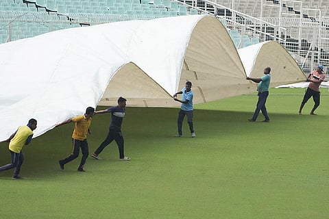 Ground staff cover the pitch as it rains during the second day of the Ranji Trophy cricket match between Bengal and Gujarat, at Eden Gardens, in Kolkata, West Bengal.