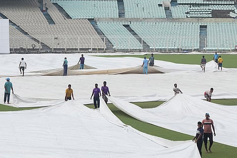 Ground staff cover the pitch as it rains during the second day of the Ranji Trophy cricket match between Bengal and Gujarat, at Eden Gardens, in Kolkata, West Bengal.