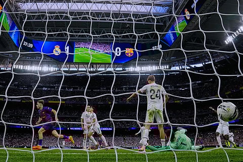 Barcelona's Fermin Lopez, left, celebrates after scoring his side's first goal past Real Madrid's goalkeeper Thibaut Courtois, bottom right, during the Spanish La Liga soccer match between Real Madrid and Barcelona, in Madrid.