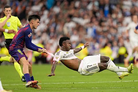 Barcelona's Pedri pulls Real Madrid's Vinicius Junior during a La Liga soccer match between Real Madrid and Barcelona in Madrid, Spain.