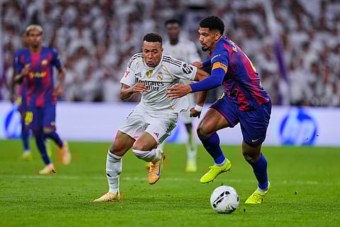 Real Madrid's Kylian Mbappe, left, fights for the ball with Barcelona's Ronald Araujo during the Spanish La Liga soccer match between Real Madrid and Barcelona, in Madrid.
