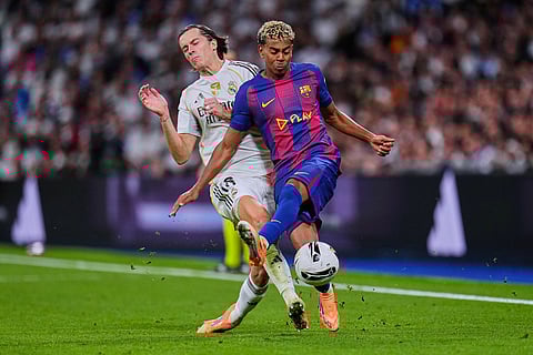Barcelona's Lamine Yamal, right, fights for the ball with Real Madrid's Alvaro Carreras during the Spanish La Liga soccer match between Real Madrid and Barcelona, in Madrid.