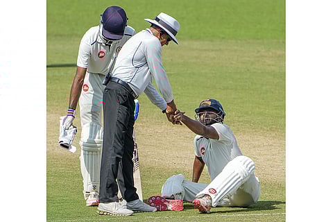 Gujarat's Urvil Patel reacts in discomfort as the on-field umpire intervenes following his complaint of wrist pain during Day 4 of the Ranji Trophy match between Bengal and Gujarat, at Eden Gardens, Kolkata.