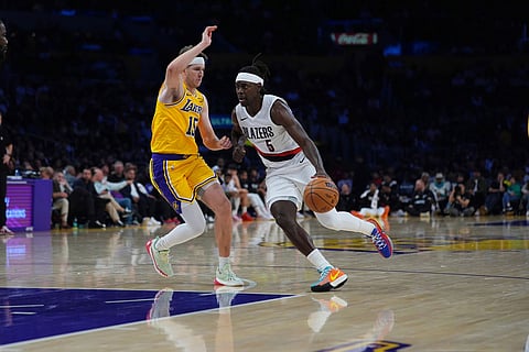 Portland Trail Blazers guard Jrue Holiday (5) is defended by Los Angeles Lakers guard Austin Reaves (15) during the second half of an NBA basketball game in Los Angeles.