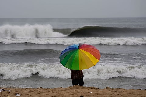 A person looks on as sea waves crash against the shore ahead of the landfall of Cyclone 'Montha', at Marina beach in Chennai.