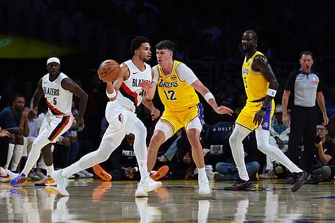 Portland Trail Blazers forward Toumani Camara, center left, is defended by Los Angeles Lakers forward Jake LaRavia (12) during the first half of an NBA basketball game in Los Angeles.