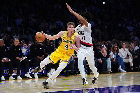 Los Angeles Lakers forward Dalton Knecht (4) is defended by Portland Trail Blazers guard Shaedon Sharpe (17) during the first half of an NBA basketball game in Los Angeles.