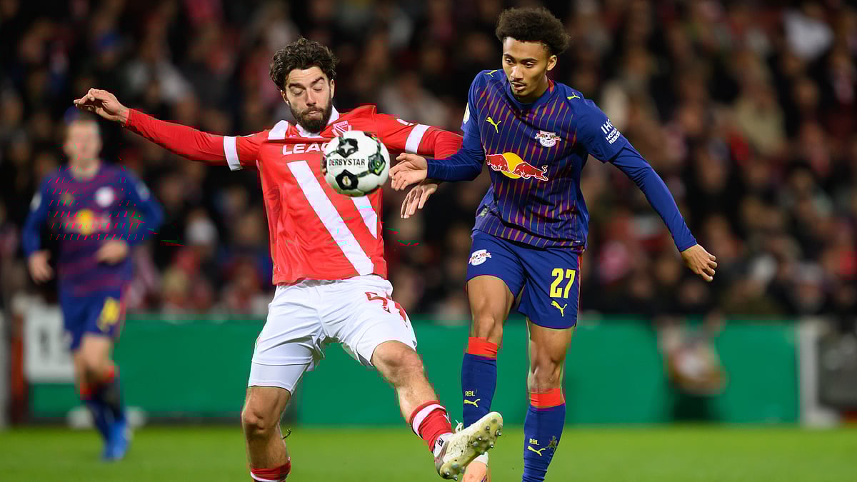 | Photo: dpa/Robert Michael via AP : Leipzig's Tidiam Gomis, right, and Cottbus' Dominik Pelivan, left, challenge for the ball during a German soccer cup second round match between Energie Cottbus and RB Leipzig in Cottbus, Germany, Tuesday, Oct. 28, 2025.