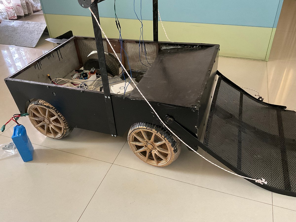 A homemade robotic vehicle with golden wheels, black body, and a metal ramp on the front side
