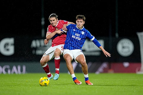 Wrexham's George Dobson, left, and Cardiff City's Rubin Colwill battle for the ball during the English League Cup fourth round soccer match between Wrexham and Cardiff City in Wrexham, Wales.