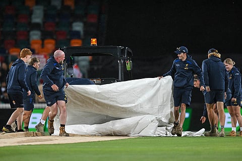 Ground staff roll out the covers as rain interrupts play during the T20 cricket international between India and Australia in Canberra, Australia.