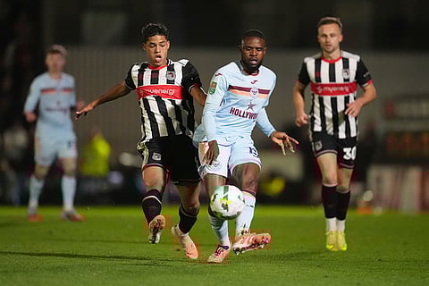Grimsby Town's Evan Khouri, center left, and Brentford's Frank Onyeka battle for the ball during the English League Cup fourth round soccer match between Grimsby Town and Brentford in Grimsby, England.