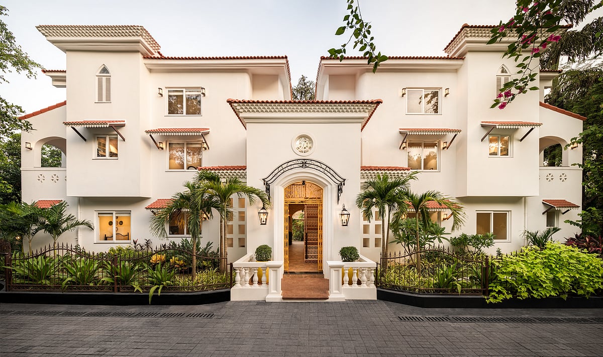 A white mansion with brown accents and lush greenery