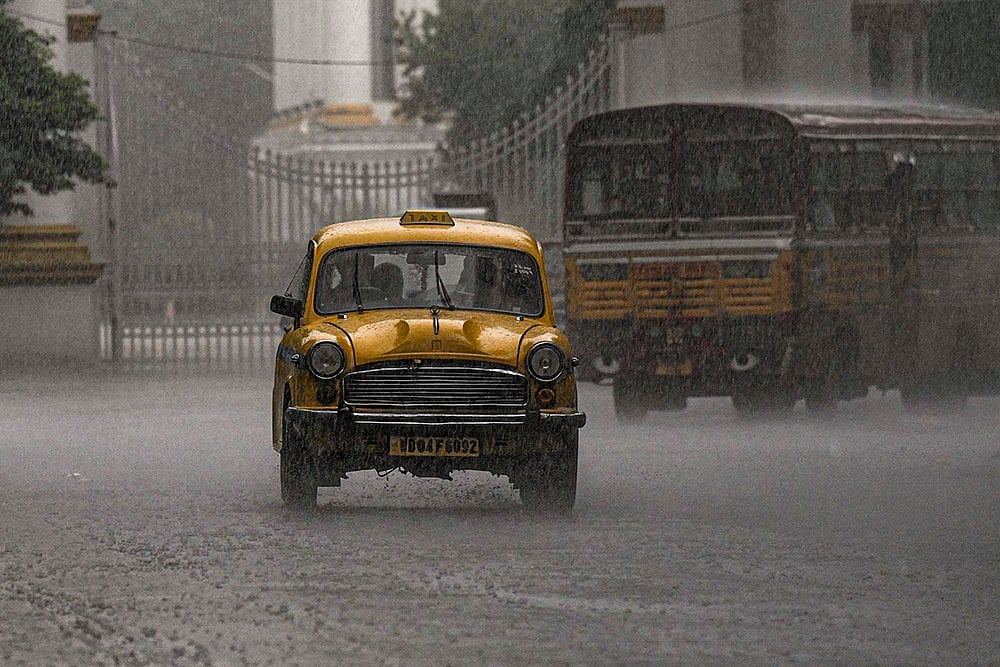 Rainfall in Kolkata: A taxi passes by during rain, in Kolkata, West Bengal. - | Photo: PTI/Manvender Vashist Lav