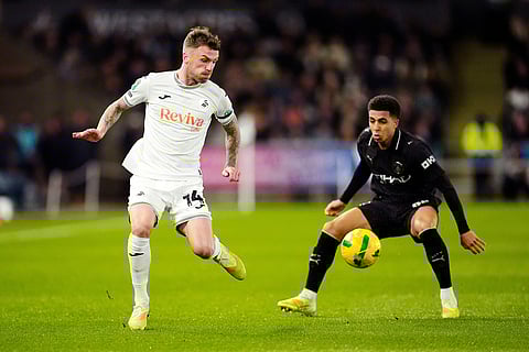 Swansea City vs Manchester City: Swansea City's Josh Tymon, left, and Manchester City's Rico Lewis in action during the English League Cup fourth round soccer match between Swansea City and Manchester City in Swansea, Wales.