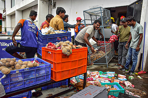 Workers try to move goods after a fire broke out at a Swiggy Instamart store, in Navi Mumbai, Maharashtra.